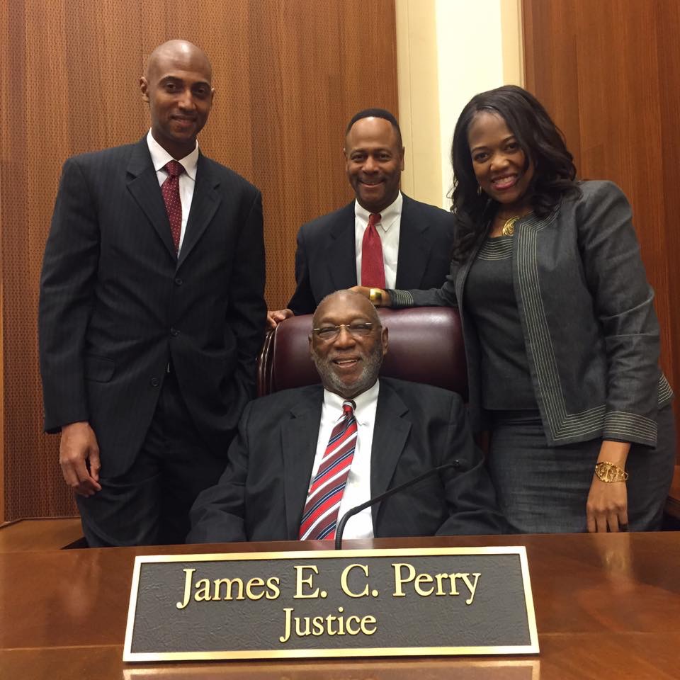 Justice Perry seated at the judicial bench alongside family members